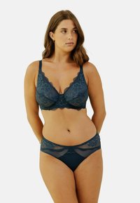 Ensemble de soutien-gorge en dentelle et de culotte en vert profond, avec des motifs floraux, un décolleté plongeant et des accents décoratifs au centre et à la taille.