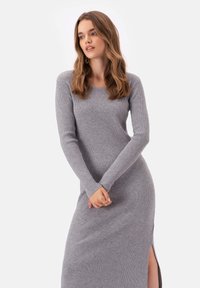 Szara dzianinowa sukienka z prążkowanej tkaniny, z długimi rękawami i bocznym rozcięciem, cechująca się okrągłym dekoltem i dopasowanym krojem. Gładka struktura i subtelne detale.
