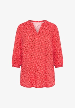 Blouse rouge à manches longues avec petits motifs de cœurs noirs et blancs, poignets élastiques et col fendu en V.