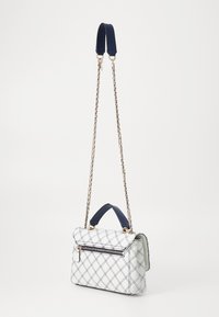Borsa a tracolla bianca trapuntata con accenti blu navy, forma rettangolare, tracolla a catena, manico superiore e tasca frontale con zip e finiture in tono oro.