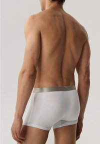 Białe slipy wykonane z elastycznej tkaniny, z gładkim srebrnym pasem, dopasowanym krojem i średnim stanem.