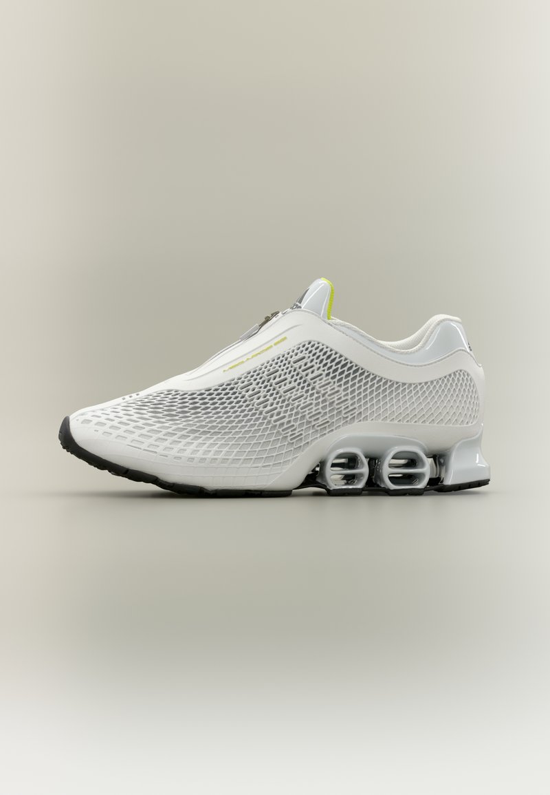 Biele športové topánky s vrchnou časťou z textílie, výraznými štruktúrovanými vzormi, reflexnými detailmi a charakteristickým dizajnom podrážky s tromi komorami.