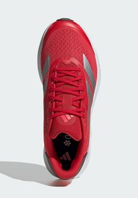 Red athletic shoe with a breathable mesh upper, silver accents, round toe, and flat rubber outsole, featuring laces and padded collar.
