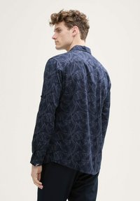 Navyblauwe langemouwen shirt met een bladerenpatroon, knoopmanchetten en een afgeronde zoom. Gemaakt van lichte stof, met een puntige kraag.
