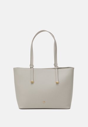 Beige Ledertasche mit doppelten Schulterriemen und kleinen goldenen quadratischen Akzenten an den Enden der Träger und am vorderen Logo.