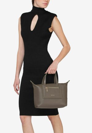 Schwarzes ärmelloses Kleid mit hohem Hals und Schlüsselöffnung, kombiniert mit einer taupefarbenen Ledertasche mit einem Reißverschluss vorne.