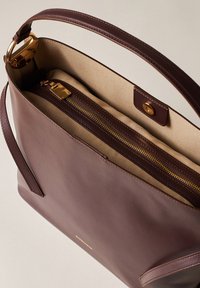 Braune Lederhandtasche mit glatter Textur. Verfügt über goldfarbene Beschläge, ein Reißverschlussfach und ein weiches, beige Innenfutter.