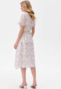 Bloemenpatroon midi-jurk in het wit met beige accenten, korte pofmouwen en een gegolfde zoom. Lichtgewicht, vloeiende stof.