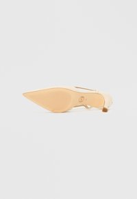 Beige väri korkokengät, joissa on terävä kärki, sileä pinta ja hoikka nilkkaremmi. Pohjassa on uritettu kumipohja pitävyyttä varten.