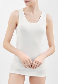 Canotta bianca e morbida con scollo rotondo e spalline sottili. Il tessuto ha una texture liscia, una linea aderente e arriva a metà coscia.