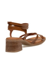 Sandalias marrones con tiras y un tacón grueso con textura de madera, que exhiben un diseño elegante adecuado para uso casual o semi-formal.