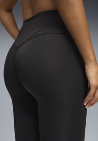Musta korkea vyötäröinen leggings materiaali, joka on sileä ja joustava. Sisältää tyylikkään muotoilun ja hillityt ommellut yksityiskohdat vyötäröllä ja jaloissa.