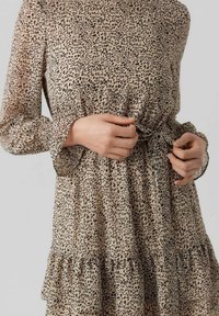 Hame takki vaale ka leopard print pattern ke saath, lambay aediyon, aur tiered frill wale hem. Kapda bahut halka aur behne waala hai, jo ke ek fitted kamar ke saath hai.