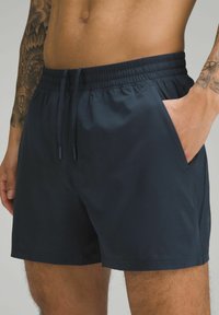 Shorts de bain navy avec une taille élastique, cordon de serrage et poches latérales. Tissu lisse et léger, design arrivé au genou.