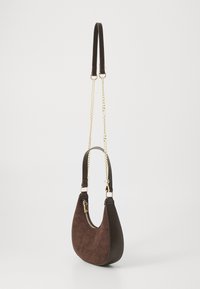 Ruskea mokka- ja nahkakreikkalainen laukku, jossa on kultainen vetoketju ja ketjuhihna. Laukussa on sekä kaksinkertainen olkahihna että ristikkäin kuljetusmahdollisuus.