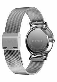 Montre Timex avec un bracelet en mesh en acier inoxydable et un boîtier en argent poli. Cadran rond avec un design minimaliste et des marquages gravés.