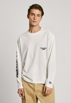 White long-sleeve T-shirt made of cotton, featuring a small logo on the chest and printed text along the left sleeve. Standard fit.