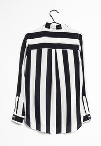 Randig långärmad blus i svart och vitt med krage, plisserad bakdel och knäppte manschetter, tillverkad av lätt material.