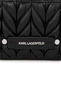 Zwart leren handtas met een gewatteerd bladenpatroon, zilverkleurige hardware en een opvallende logo-tag.