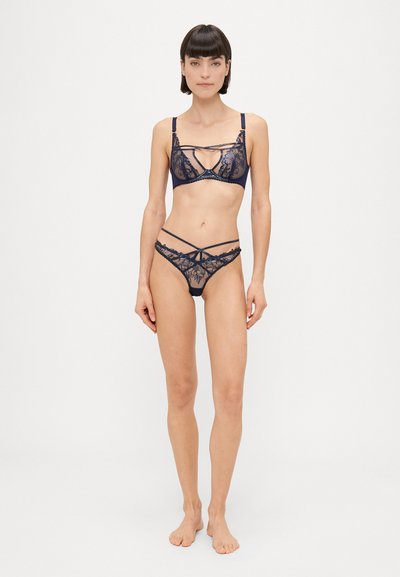 Navy čipkasti komplet spodnjega perila, ki vključuje bralette z zapletenimi cvetličnimi vzorci in izrezi, v kombinaciji z ujemajočim se nizkim tangicami.