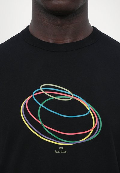 T-shirt noir avec un design graphique coloré de cercles superposés en bleu, vert, rose, violet et jaune. Logo de la marque en bas.