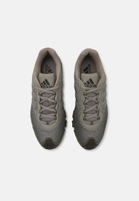 Gray athletic shoes with breathable mesh material, reinforced toe, and textured sole. Features a lace-up design and subtle branding accents.