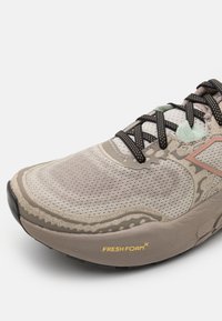 Baskets de course beige avec une tige en maille, des détails texturés, des lacets noirs et une semelle intermédiaire confortable avec le marquage "FRESH FOAM".