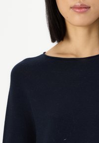 Mørkeblå strikkegenser med rund hals og myk, teksturert stoff med ribbede kanter, som fremhever et enkelt og rent design.