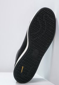 Svart sneakersula med en texturerad gummiyta, som har ett framträdande vitt streck och cirkulära mönster. Inkluderar "continental"-logotyp.