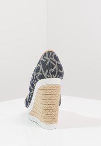 Scarpa wedge realizzata in denim blu navy testurizzato, con accenti in gomma bianca e un tacco in iuta intrecciata. Presenta una punta affusolata e una silhouette alta.