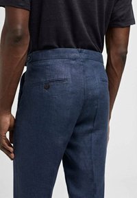 Pantaloni in lino blu navy con una texture liscia, caratterizzati da un classico taglio diritto, due tasche posteriori e una chiusura con bottone.