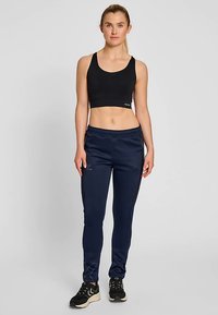 Svart sport-bh och marinblå smala joggers med sidofickor och loggdetalj. Joggers har elastisk midjeband och kontrasterande sidopanel.