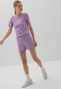 Lawendowa koszulka z krótkim rękawem i pasujące szorty z miękkiego, lekkiego materiału. Ubranie posiada elastyczny pas i luźny krój.