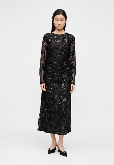 Must pikkade varrukatega läbipaistev kleit lilleliste litrifröösidega, kehavoltidega ja midi-pikkuse äärega. Kandmiseks mustade teravnurkade kontsakingadega.