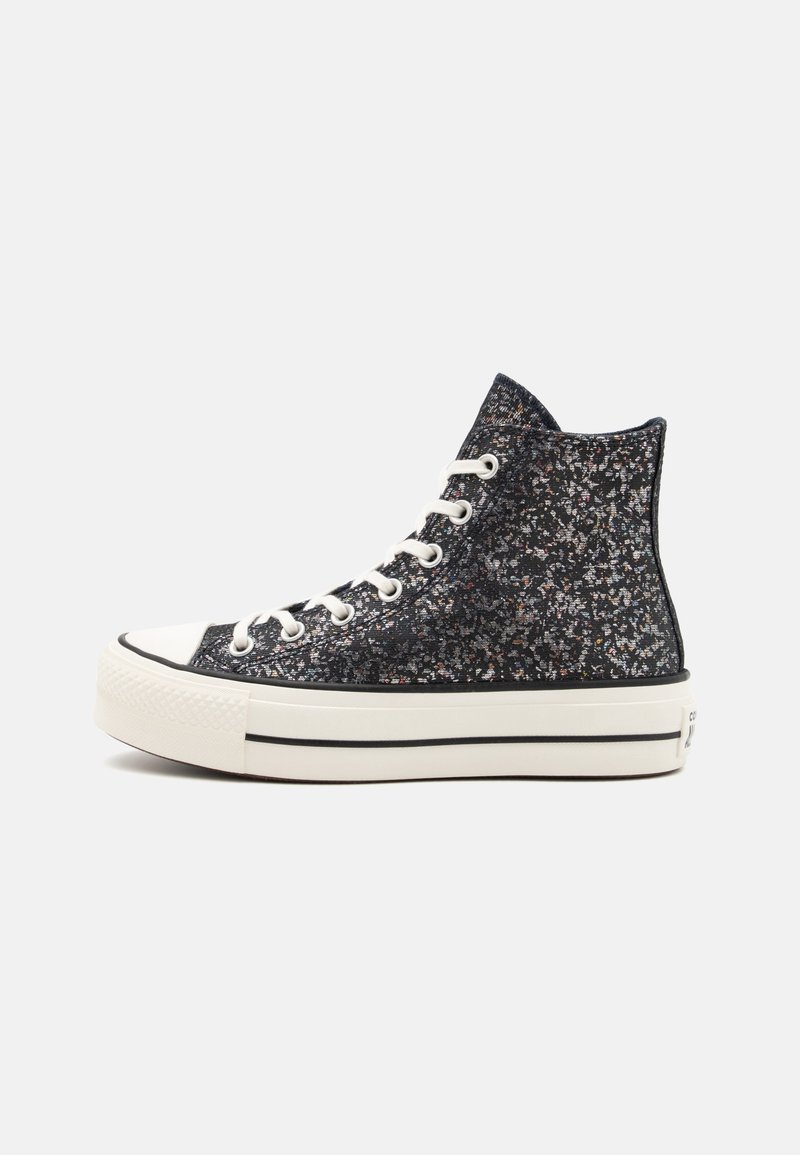 Des baskets montantes en tissu à paillettes noires et multicolores, avec un embout en caoutchouc blanc et une semelle blanche à rayures noires.