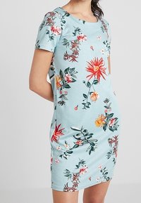 Květinové šaty s krátkým rukávem v světle modré barvě s barevnými květinovými vzory. Vyrobené z měkké látky, s kulatým výstřihem a přiléhavým střihem.