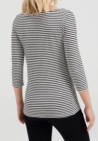 Svart och vitrandig långärmad topp med båthals, figurnära design och mjuk textur, sedd bakifrån.