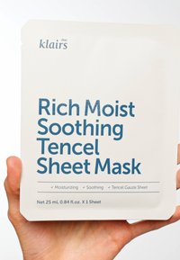 Tencel ansiktsmaskeinnpakning i kremfarge med fet blå tekst. Inneholder fuktighetsgivende og beroligende påstander, netto vekt 25 mL, én maske.