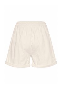 Shorts en coton blanc avec une taille élastique, présentant des ourlets roulés et une coupe décontractée. Le tissu a une texture douce et légèrement froissée.