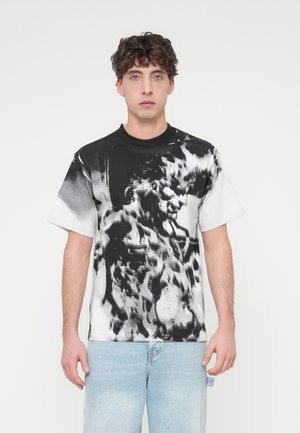 T-shirt med korta ärmar i bomull, med ett svartvitt abstrakt mönster och en framträdande grafisk tryck. Rund halsringning och avslappnad passform.
