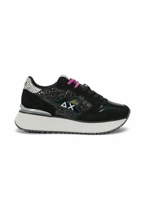 Sneaker nero con lato scintillante, suola bianca spessa, dettaglio sul tacco in argento, lacci viola e neri e logo a forma di stella con simboli delta e chi.