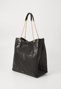 Sac fourre-tout en cuir noir avec un motif matelassé, doté de poignées en chaîne dorée et d'un haut froncé, offrant une silhouette moderne et structurée.