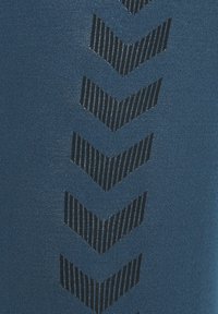 Niebieskie legginsy sportowe z teksturowanym czarnym wzorem w jodełkę po jednej stronie, wykonane z gładkiego, elastycznego materiału.