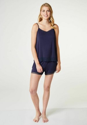 Navyblauwe pyjamset met kantafwerking. Bevat een mouwloos topje en shorts. Zacht materiaal, ontspannen pasvorm. Kantdetails aan de zoom en randen van de shorts.