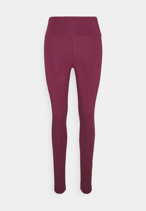 Leggings bordeaux en tissu extensible, dotés d'une taille haute et d'un logo subtil sur la hanche, avec une texture lisse et un design ajusté.