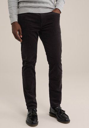 Pantalones de pana negra con un ajuste slim, que presentan una textura suave y líneas de textura sutiles. Combinados con zapatos negros y un suéter gris.