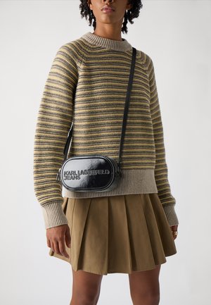 Maglione a righe nei toni beige e giallo, abbinato a una gonna plissée khaki e a una borsa a tracolla in pelle nera con marchio impresso.