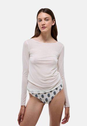 Haut à manches longues, beige clair, en tissu doux, superposé sur un sous-vêtement blanc à motifs floraux bleus. Design simple et silhouette ajustée.