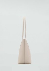 Bolso tote de cuero beige con una forma estructurada, dos asas largas y una base plana, que presenta una textura suave y un diseño minimalista.