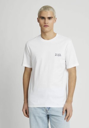 T-shirt en coton blanc à manches courtes et col rond, avec un petit texte noir brodé sur la zone de la poche poitrine gauche.
